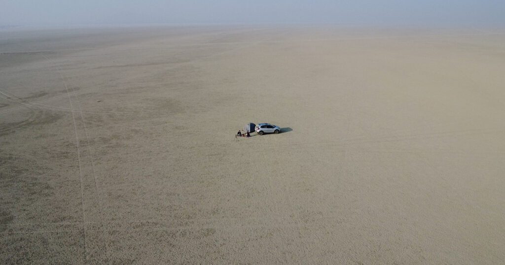 Morning camping at Sambhar Salt Lake Rajasthan – aerial view of tent and car in the middle of the salt desert, ideal for peaceful camping, sunrise views, and birdwatching near flamingos.