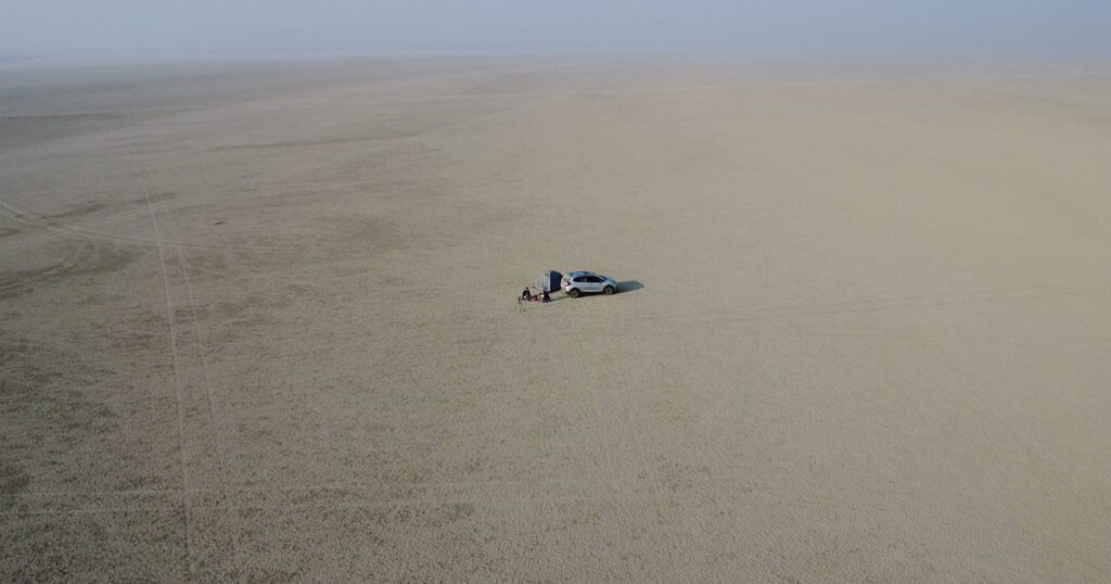 Morning camping at Sambhar Salt Lake Rajasthan – aerial view of tent and car in the middle of the salt desert, ideal for peaceful camping, sunrise views, and birdwatching near flamingos.