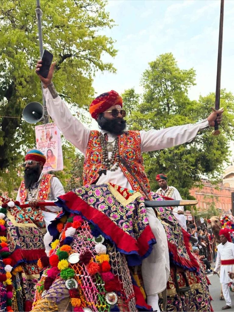 Rajasthani folk artist riding a decorated camel during Jaipur's traditional Teej procession