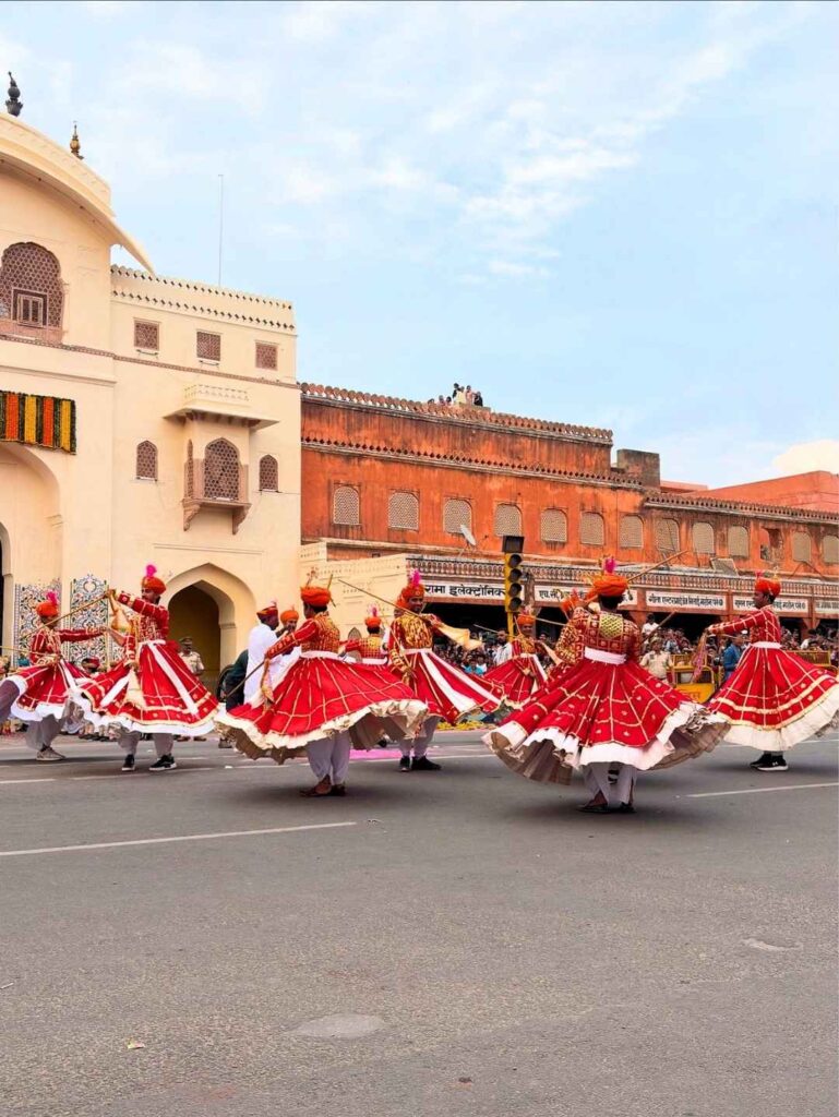 Rajasthani folk dancers performing in traditional costumes during the Teej Festival procession in Jaipur